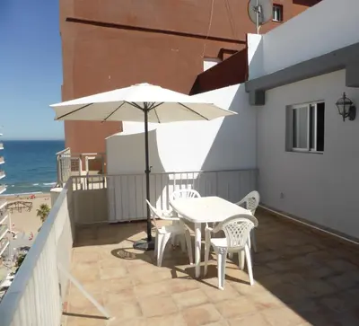 a patio with a table and chairs and an umbrella at Ático a 100 metros de la playa in Cullera