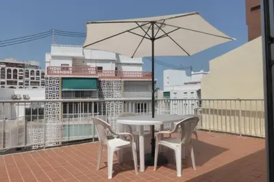 a white table and chairs with an umbrella on a balcony at Ático a 100 metros de la playa in Cullera
