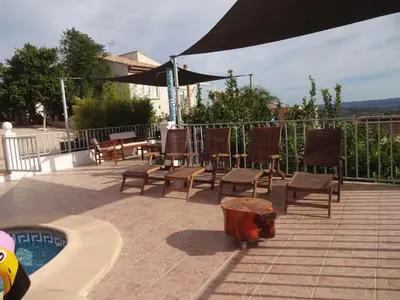 a patio with chairs and an umbrella next to a pool at LAS PALOMAS, appartement 2 chambres avec piscine in Turís