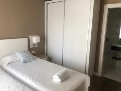 a white bed with a pillow on it in a bedroom at San Miguel, Luxury apartments. in Valencia