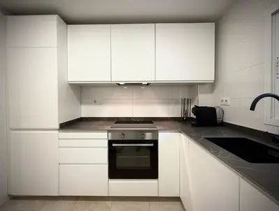 a kitchen with white cabinets and a black oven at Apartamento Playa Valencia Beach in Valencia