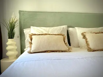 a white bed with a green headboard and white pillows at Apartamento Playa Valencia Beach in Valencia