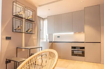 a kitchen with white cabinets and a chair at Valencia Luxury - Sea Port I in Valencia