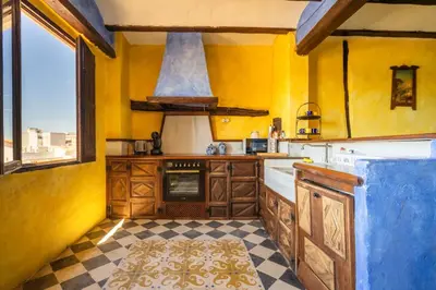 a kitchen with yellow walls and a large window at Casa Museo RAKKANA - En el Centro de Requena in Requena