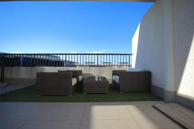a balcony with wicker chairs and tables on a building at ÁTICO PATACONA BEACH PLAYA in Valencia