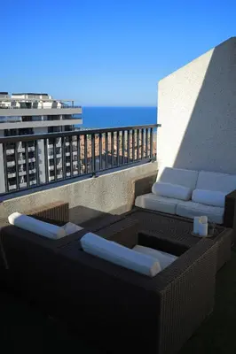 a balcony with a couch and chairs on a building at ÁTICO PATACONA BEACH PLAYA in Valencia