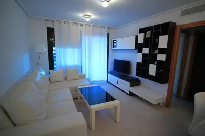 a living room with a white couch and a tv at ÁTICO PATACONA BEACH PLAYA in Valencia