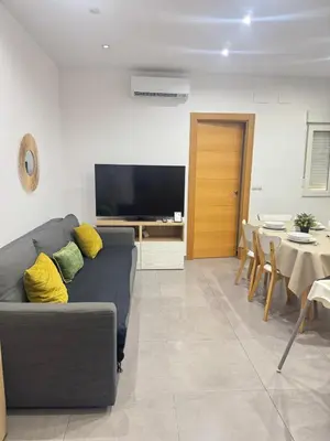a living room with a gray couch and a television at UIM Mediterraneo Segorbe 1 Wifi in Puerto de Sagunto