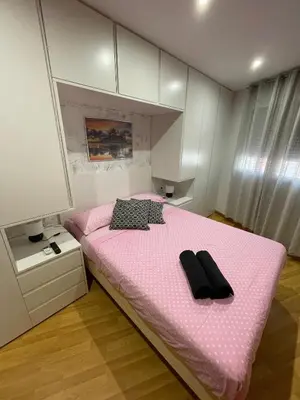 a bedroom with a pink bed with two black shoes on it at Apartamento San cayetano in Torrent