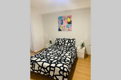 a bedroom with a bed with a black and white comforter at VALENCIA / PLAYA CABANYAL, PUERTO, CUIDAD ARTES in Valencia