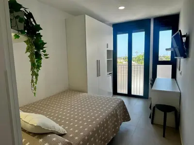 a bedroom with a bed and a desk and a window at STUDIO Palomar - PalomarGroup in Alfara del Patriarca