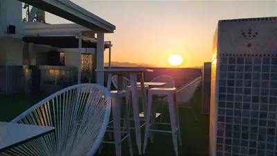 a sunset on a balcony with a table and chairs at Hotel Vent de Mar in Puerto de Sagunto