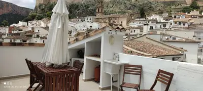 a umbrella and chairs on a balcony with a city at El Enclave in Chulilla