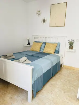 a white bed with blue and yellow pillows on it at UIM Mediterraneo Poeta 4 Wifi in Puerto de Sagunto