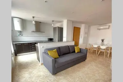 a living room with a gray couch and a kitchen at UIM Mediterraneo Poeta 5 Wifi in Puerto de Sagunto