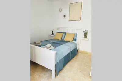 a bedroom with a white bed with blue and yellow pillows at UIM Mediterraneo Poeta 6 Wifi in Puerto de Sagunto