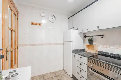a kitchen with a refrigerator and a clock on the wall at Maritim Horizon House Port of Valencia in Valencia