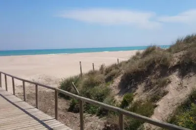 a sandy beach with a wooden boardwalk and the ocean at UIM Mediterraneo Poeta 1 Wifi in Puerto de Sagunto