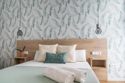 a bedroom with a bed with a green and white wallpaper at FLORIT FLATS - Valencia Port Rooms I in Valencia