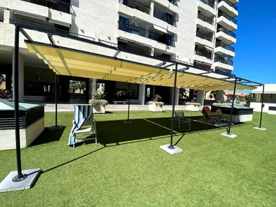 a large yellow umbrella on a lawn in front of a building at M & B Beach Apartment in Valencia