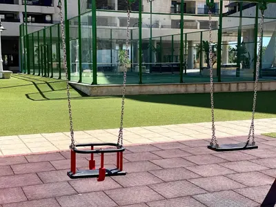 two swings in front of a building at M & B Beach Apartment in Valencia