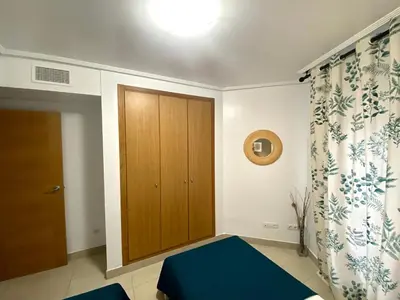 a bedroom with a wooden cabinet and a blue bed at M & B Beach Apartment in Valencia