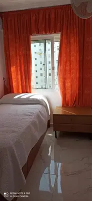 a bedroom with an orange curtain and a bed and a window at Saint Germain 2C in Cullera