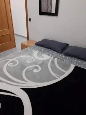 a bed with a black and white blanket on it at habitación grande en piso compartido con 2 adultos in Valencia