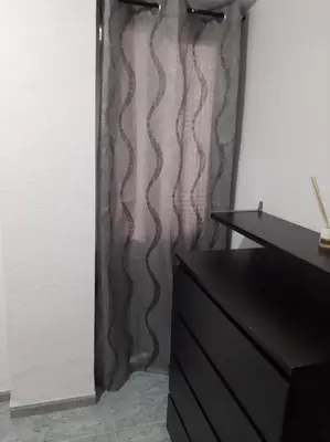 a black dresser in a room with a curtain at habitación grande en piso compartido con 2 adultos in Valencia