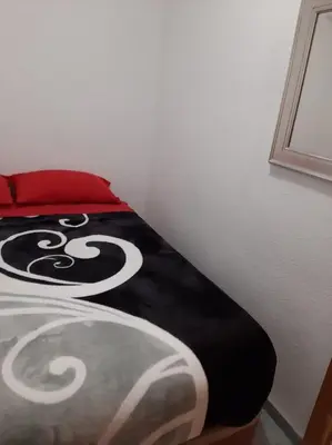 a bedroom with a bed with a black and white comforter at habitación pequeña en piso compartido con 2 adultos in Valencia