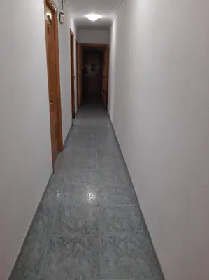 a hallway with a long corridor with a door and a tile floor at habitación pequeña en piso compartido con 2 adultos in Valencia