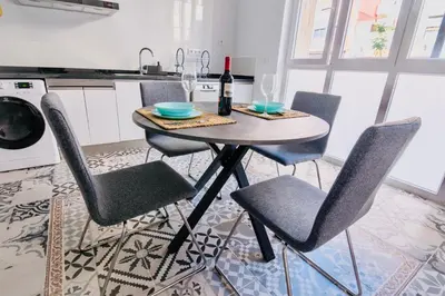 a kitchen with a table with chairs and a bottle of wine at Arenas beach in Valencia