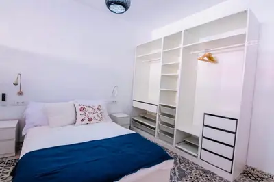 a white bedroom with a bed and shelves at Arenas beach in Valencia