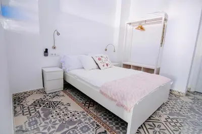 a white bedroom with a bed with a mirror at Arenas beach 2 in Valencia