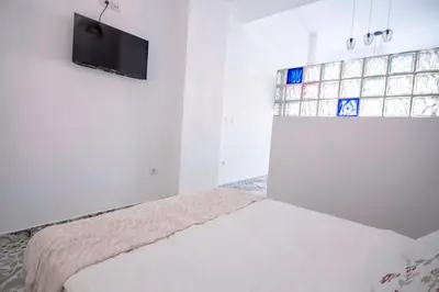 a white bedroom with a bed and a tv on the wall at Arenas beach 2 in Valencia