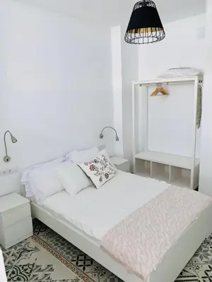 a white bedroom with a bed and a lamp at Arenas beach 2 in Valencia