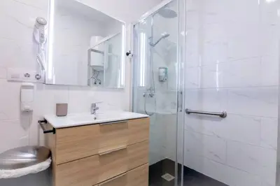 a white bathroom with a sink and a shower at Arenas beach 3 in Valencia
