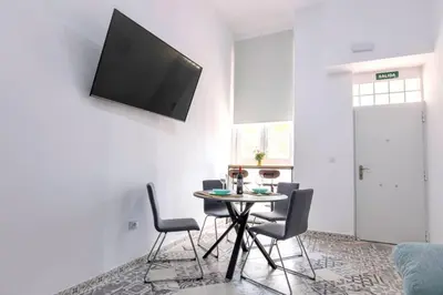 a dining room with a table with chairs and a tv on the wall at Arenas beach 3 in Valencia