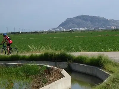 a person riding a bike next to a body of water at Aitana in Fortaleny