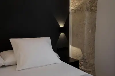 a bed with a white pillow and a black wall at Fetén in Valencia