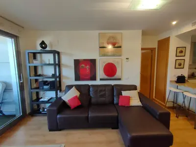 a living room with a brown leather couch with colorful pillows at NON STRESS Arena Primera línea de Playa in Valencia