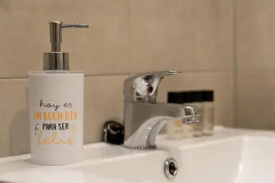 a white soap dispenser sitting on a bathroom sink at Apartamentos Mercado Central in Valencia