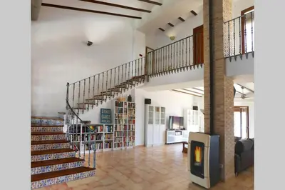 a spiral staircase in a room with bookshelves at Ca Buganvilla. El corazón de la huerta valenciana in Meliana