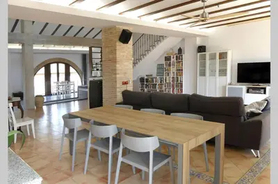 a living room with a couch and a table and chairs at Ca Buganvilla. El corazón de la huerta valenciana in Meliana