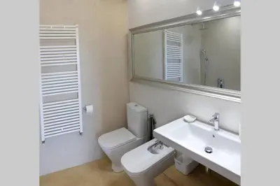 a bathroom with a sink and a toilet and a mirror at Ca Buganvilla. El corazón de la huerta valenciana in Meliana