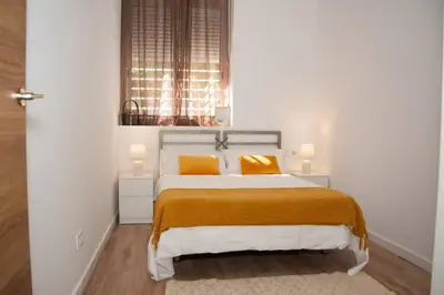 a white bedroom with a bed with two yellow pillows at Soraya's Place - Chopín 1 in Valencia