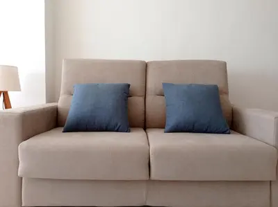 a couch with two blue pillows on it at Apartamento en El Prado in Cullera
