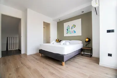 a bedroom with a large white bed and wooden floors at VLC HOST- Eixarchs in Valencia