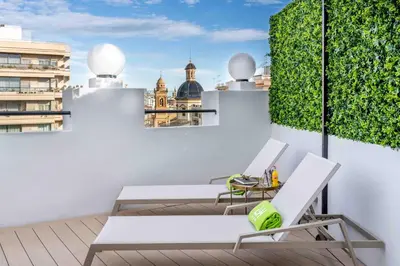 a balcony with white furniture and a view of the city at L&H Gran Vía Valencia in Valencia