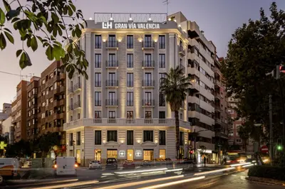 a tall white building with a sign on it at L&H Gran Vía Valencia in Valencia